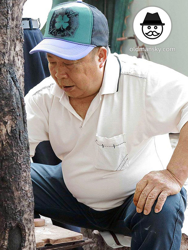 Old daddy wore white polo shirt was playing Chinese chess in the park_05