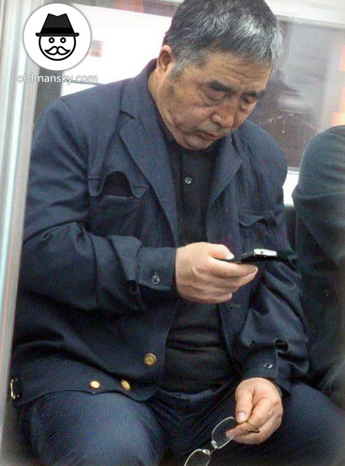 Glasses old daddy wore black suit was watching cellphone by subway