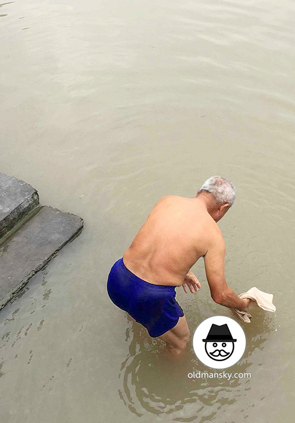 White hair old man wore a brown underwear was washing his head by the river_04