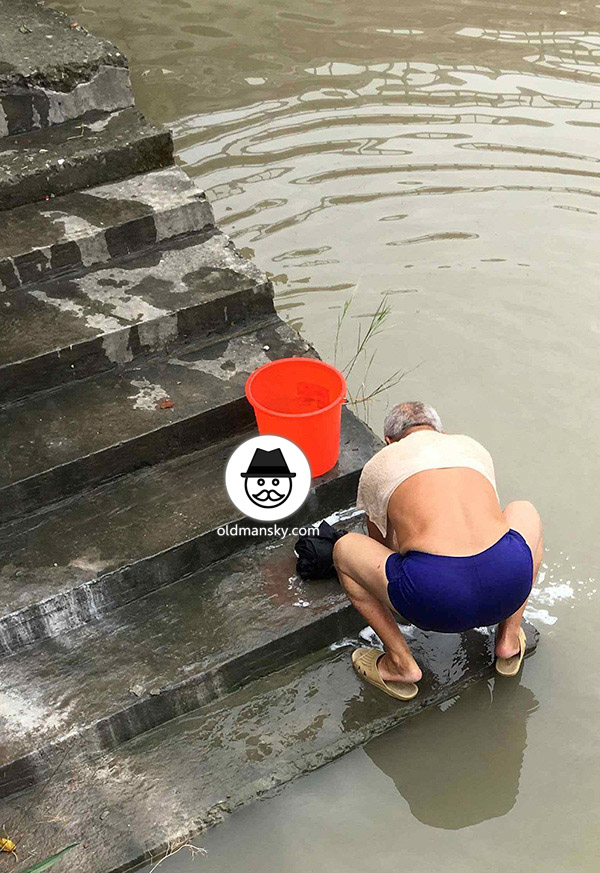 White hair old man wore a brown underwear was washing his head by the river_05